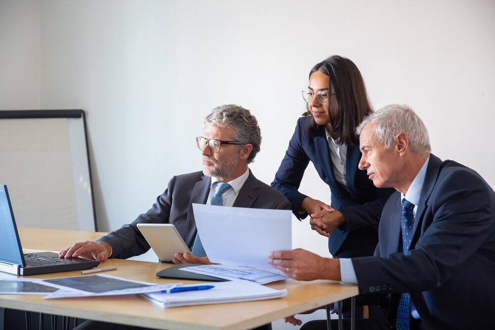 A law firm team reviewing documentation with a laptop