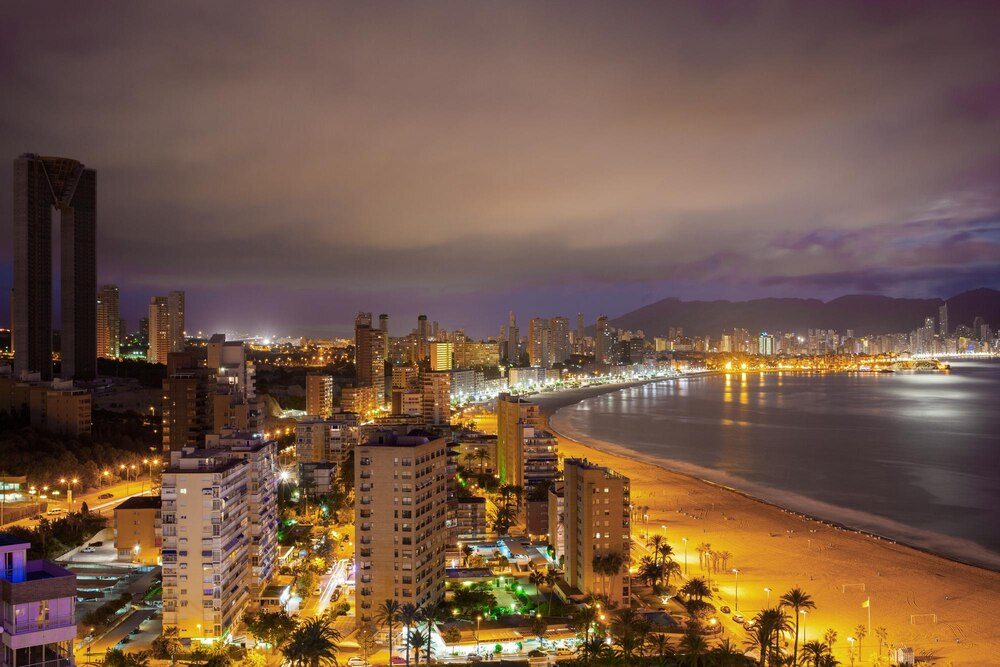 Panorama de una ciudad costera al atardecer con las luces reflejadas en el mar